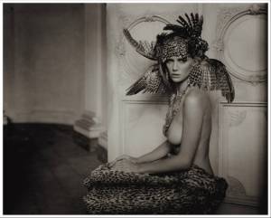 Sepia toned photograph of a nude woman wearing a feathered head dress. For On Reading Sex by Malin James
